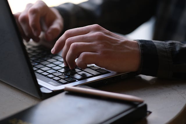 Hands typing on a laptop